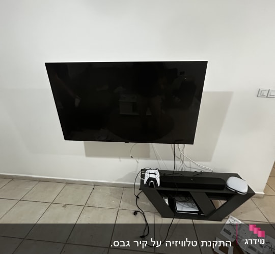טלוויזיה תלויה על הקיר עם כבלים ושלטים